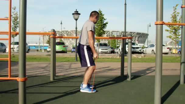 Hombre musculoso mayor haciendo ejercicios de tracción con banda elástica al aire libre. Entrenamiento — Vídeos de Stock