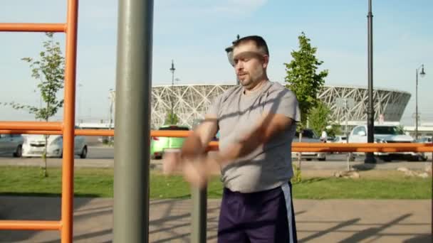 Homme âgé en t-shirt gris tournant ses mains pour se réchauffer à l'extérieur — Video