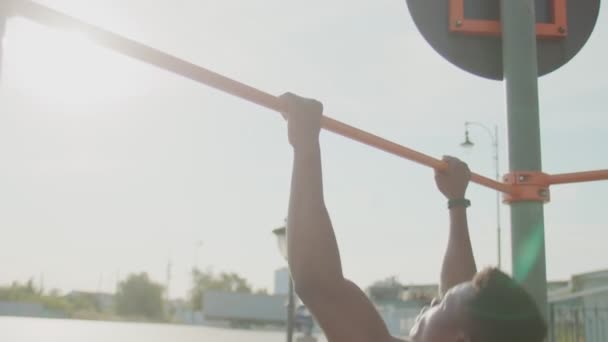 Achteraanzicht van Afrikaanse man die pull-ups doet op horizontale training buiten — Stockvideo