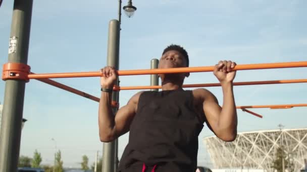 Youmg homme africain faisant pull-ups sur l'entraînement horizontal à l'extérieur — Video