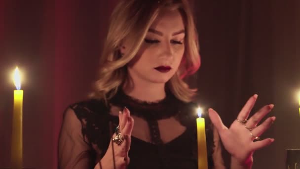 Kobieta wróżka przesuwa ręce nad magiczną świecą. — Wideo stockowe