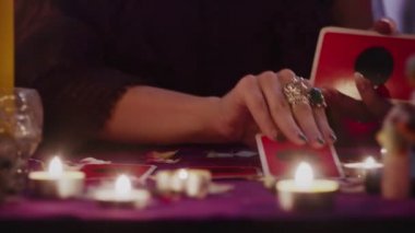 Tarot kartlarını karıştıran ve ayarlayan iki elin görüntülerini kapat