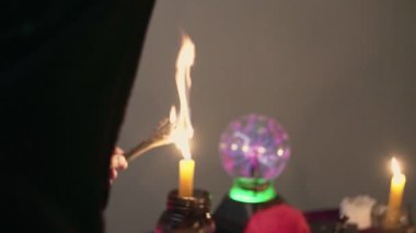 Sihirli bir salondaki erkek falcı tütsü yakar ve siyah bardağa koyar.