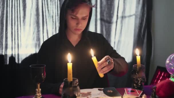 Männliche Wahrsagerin, die ein magisches Pendel über einer Kerze hält und ein Foto mit einer verlorenen Person betrachtet — Stockvideo