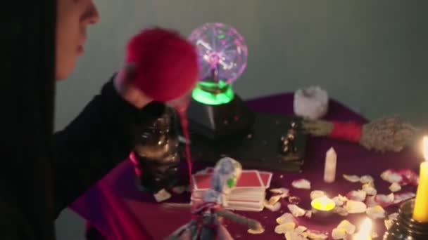 Magia negra bruxa vodu realizando ritual e lançando feitiço piercing boneca com agulhas sentadas no quarto escuro com velas acesas. — Vídeo de Stock