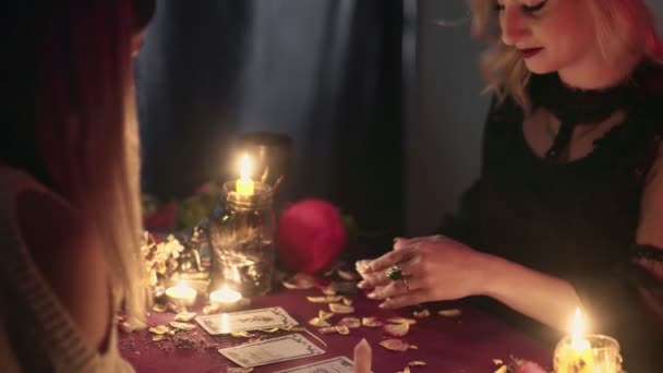 Вид збоку жінка використовує картки таро для прогнозування майбутнього свого молодого клієнта — стокове відео