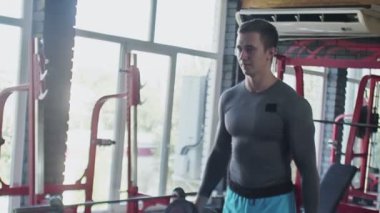 Spor salonunda halterlerle kıvrım egzersizi yapan yakışıklı bir sporcu.