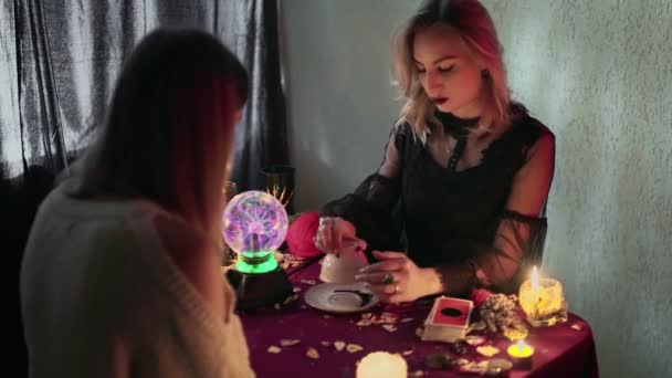 Client and fortune teller holding empty cup with coffee grounds and reading fortune. — Stock Video