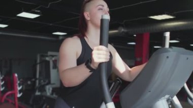 Eğitimden önce kaslı kadın eliptik makineyle ısınıyor.