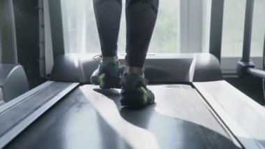 Spor ayakkabılı kadın ayakları koşu bandında yürür.