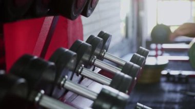 Erkek vücut geliştirici hafif dambıl koyar ve ağırlaşır.