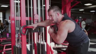 Çekici bir vücut geliştirici Simülatör Makinesinde Silahların Kasları İçin Egzersiz Yapıyor
