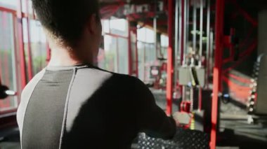 Spor salonundaki alçak sıra makinesinde spor yapan atletik adamın arka görünüşü