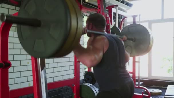 Um fisiculturista homem atraente faz agachamentos com barra no ginásio — Vídeo de Stock