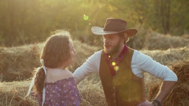 Jovem cowboy e bela mulher linda fala na fazenda com luz do sol no fundo — Vídeo de Stock