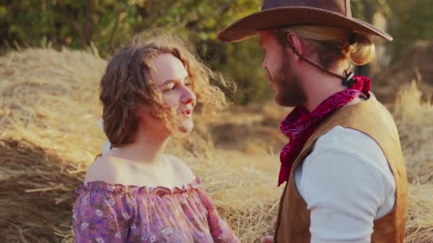Giovane cowboy e bella donna bella parla in fattoria con la luce del sole su sfondo — Video Stock