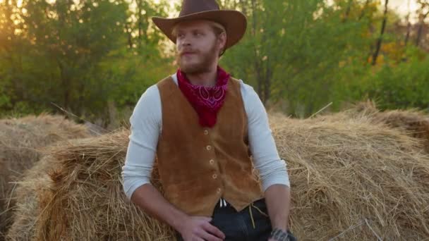 Jóképű cowboy pózol széna mellett a farmján. — Stock videók