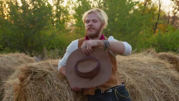 Knappe cowboy poseren in de buurt van hooi op zijn boerderij — Stockvideo