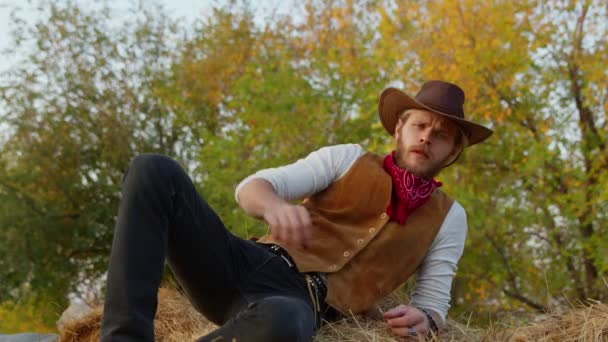 Knappe cowboy poseren in de buurt van hooi op zijn boerderij — Stockvideo