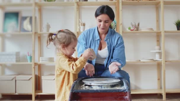 Femme potier fait un pot sur la roue de la poterie avec sa fille — Video