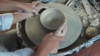 Kadın oğluna kilden tencere yapmayı öğretiyor.