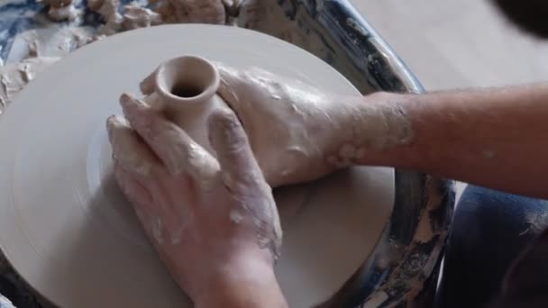 Mão trabalha na roda de cerâmica, moldando um pote de barro, estudante faz de pote de barro no estúdio — Vídeo de Stock