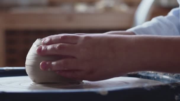 Vista laterale di piccoli ragazzi mani lavorano sulla ruota di ceramica, modellando una pentola di argilla — Video Stock