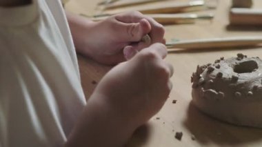 Küçük çocuk çömlekçilik dersinde kille oynuyor.