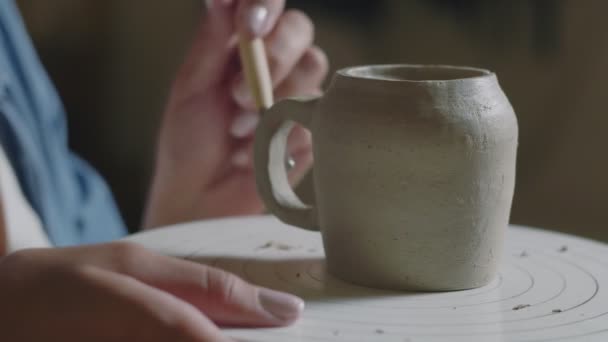 Закрытие женского горшечника с помощью инструментов для изготовления керамической глиняной ручки чашки в мастерской гончаров — стоковое видео