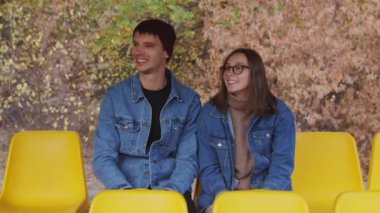 Romantik Kafkasyalı çift parkta sarı bankta oturmuş konuşuyor.