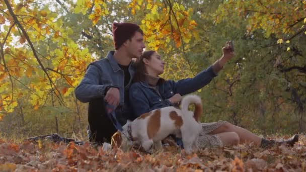 Romântico jovem casal com jack russell terrier cão leva uma selfie na natureza — Vídeo de Stock