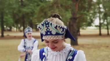 Mavi Rus Geleneksel Halk Kostümleri içinde genç ve güzel bir kadın yaz ormanında dans ediyor.