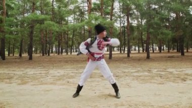 Genç adam yaz ormanlarında geleneksel Rus dansı yapıyor.