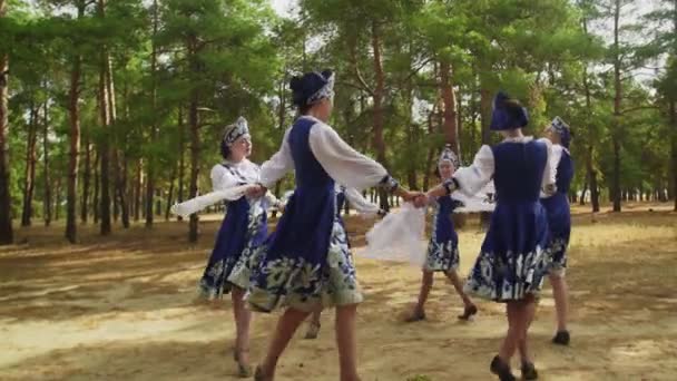Шесть молодых женщин в русских традиционных народных костюмах танцуют в летнем лесу — стоковое видео