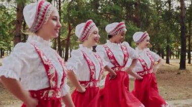 Dört genç kadın yaz ormanlarında geleneksel Rus danslarıyla dans ediyor.