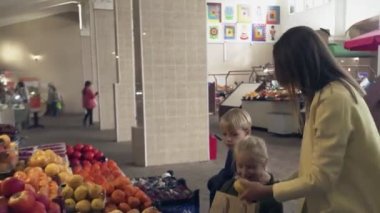 Annesiyle küçük bir çocuk marketten taze meyve seçiyor..