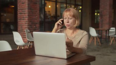 Son sınıf öğrencisi kadın telefonla konuşuyor ve modern kafede deftere yazıyor.