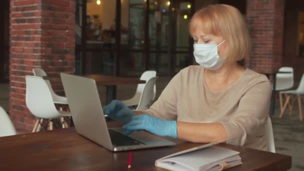 Escritora de libros con máscara protectora y guantes trabaja en cafetería — Vídeos de Stock