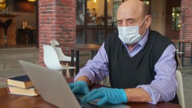 Koruyucu maskeli ve eldivenli yaşlı erkek meme ucu üniversite kantininde ya da üniversite kafeteryasında çalışıyor.