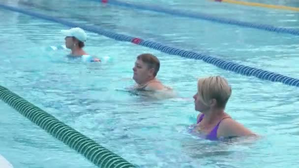 Trzy starsze kobiety trenujące gimnastykę wodną w basenie. — Wideo stockowe