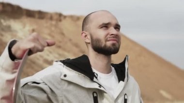 Çölde ya da taş ocağında kumla poz veren yakışıklı kel sakallı adama yaklaş.