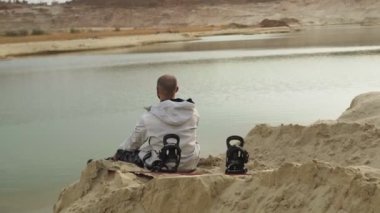 Yakışıklı, kel sakallı adam çölde ya da taş ocağında kumla takılıyor.