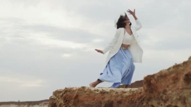 Güzel esnek kadın kumlu çölde dans ediyor.