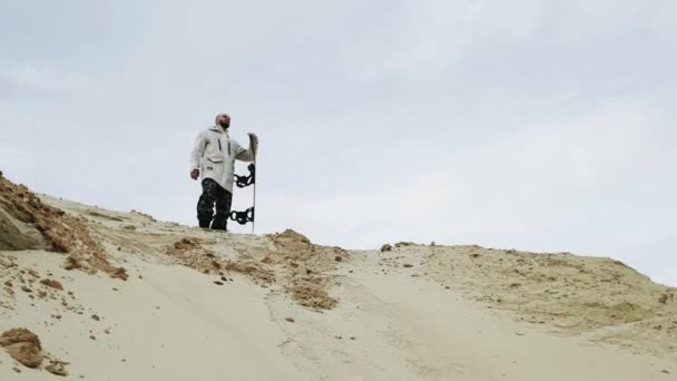 Snygg man på toppen av sandberget med sandbrädor i öknen eller sandstenbrott — Stockvideo