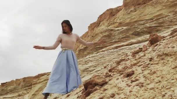 Beautiful and dreamy young woman dances on a background of mountains — Stock Video