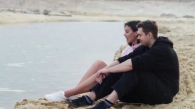 Genç çift çölde kumda oturur ve konuşur.
