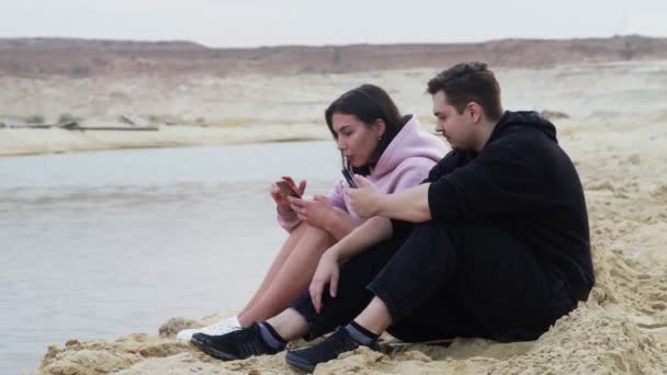 Giovane coppia si siede sulla sabbia nel deserto e parla — Video Stock