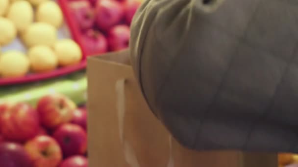 Primo piano della donna mette le mele rosse in un sacchetto di carta al mercato — Video Stock
