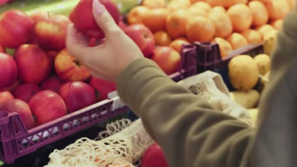 Gros plan de la femme met des pommes rouges dans un sac à ficelle au marché — Video