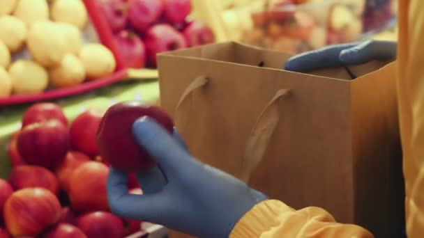 Gros plan de l'homme met des pommes rouges dans un sac en papier au marché — Video